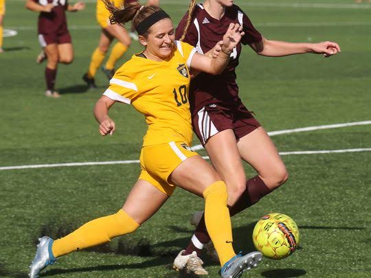 Two soccer players from opposing teams vying over possession of the ball.