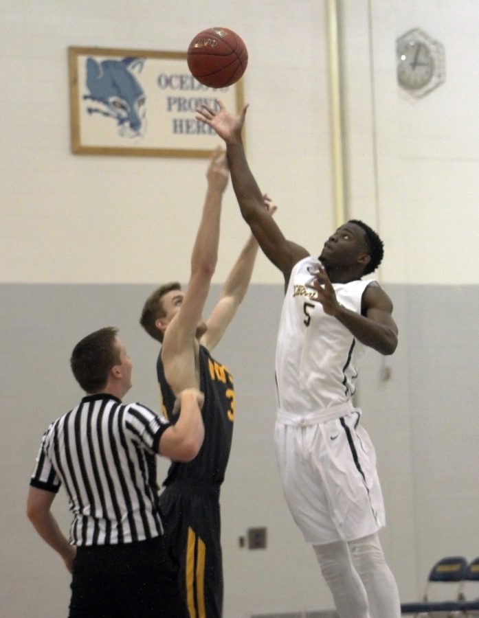 Schoolcraft’s Tariq Jones goes in for a tip off against Mott Community College player, Sean Corcoran. (Photo by Atticus Laird, Photo Editor)