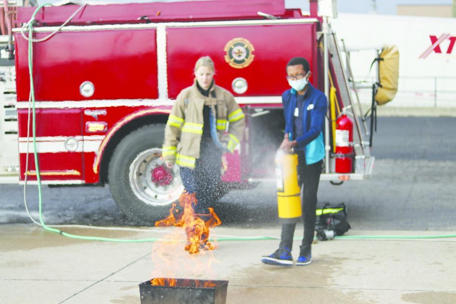 A Clarenceville Middle School student learns how to properly put out a fire using a fire extinguisher under the supervision of a Schoolcraft Fire Academy student on Nov. 5, 2021 at the Public Safety Training Center.