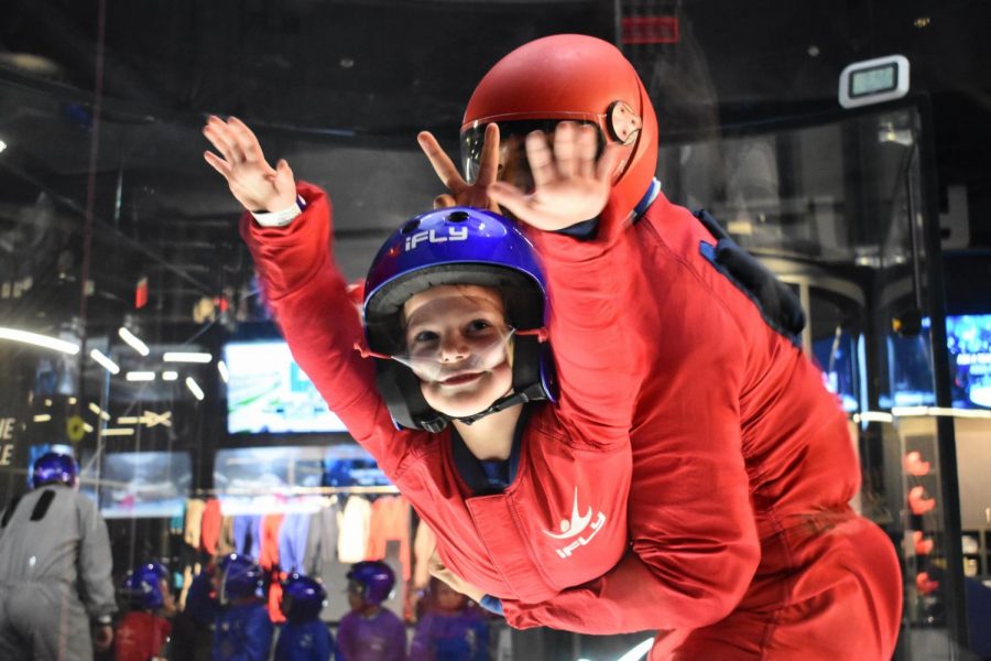 A young flyer extends his hands out in joy during his flight in iFLY’s wind tunnel.