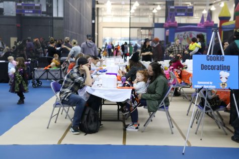 Attendees take a break and work on decorating their cookies at the Decorate a Cookie tables at the Spooktacular on Friday, October 28, 2022 in the Elite Sports Center at Schoolcraft College.