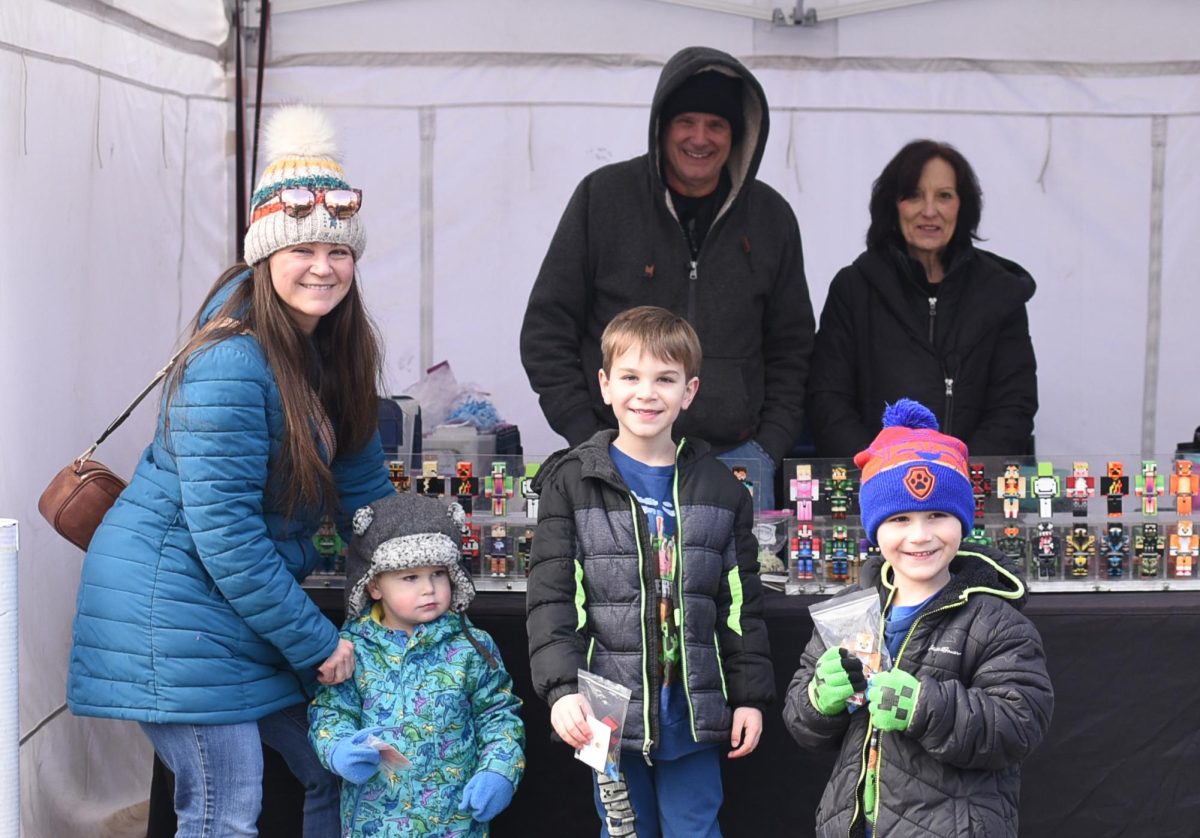 A mother with her children pose for a photo after assembling personalized Minecraft Action Figures at the Red Lava Toys tent during the Plymouth Ice Festival Feb. 3, 2024 in downtown Plymouth, Michigan.
