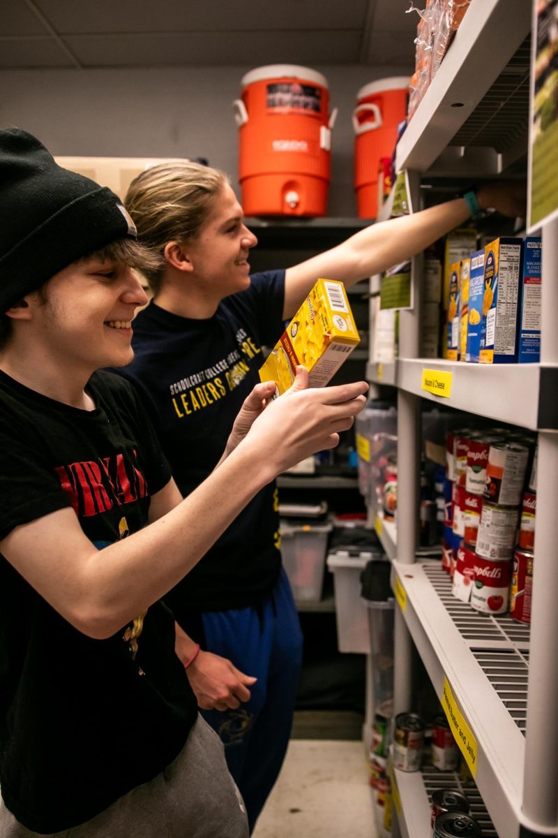 Student Activities Office student employees Jake Bolstrum and Noah Walters (right) restock the food pantry shelves.