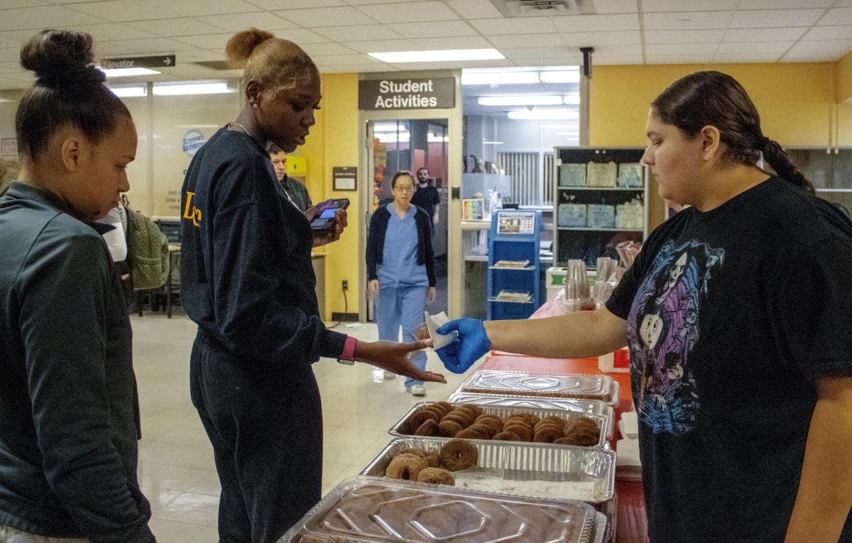 Student Activities Office student employee Aubrey Allie hands a student a donut during the Cider and Donuts event sponsored by the Student Activities Board on Tuesday, September 24, 2024 in the Lower Level, Vistatech Center.