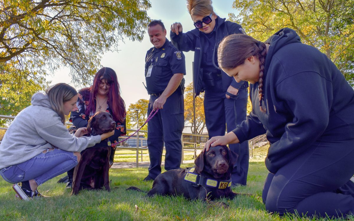 Comfort dogs Copper and Starla proudly providing comfort and smiles to students (from left to right) Victoria Kerr, Reed Mulsoff, and Aubree Allie. Schoolcraft Police Lt. Matthew Mayes and Sgt.Carla Murray oversee. 