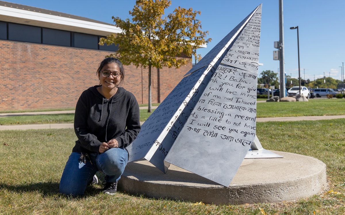 Homayra Adiba kneels next to her sculpture named “A Letter To My Father”. The sculpture can be found between the Health Sciences Building and the BioTech Center .