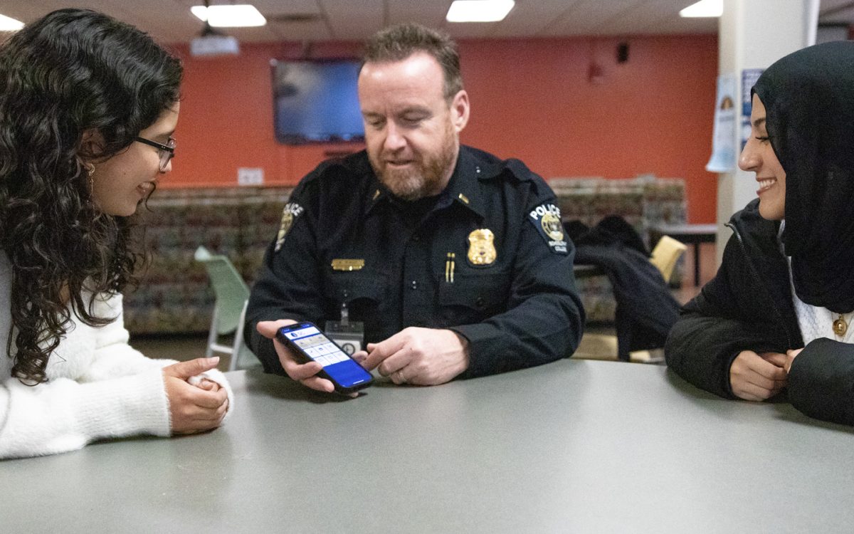 Schoolcraft College Police Lieutenant Matthew Mayes (center) explains the SC Safe app to students. The newly launched app aims to support
student safety.