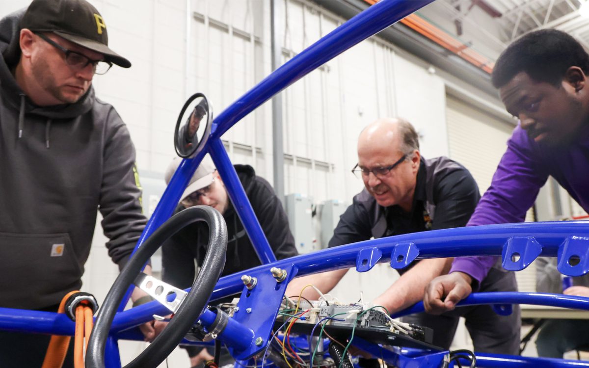 (Left to Right) Students Paul Novak, Brandon Fillenworth, Professor Gerry Lickey and Willlie Simmons discussing the switch battery building.