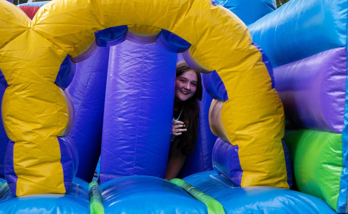 Olivia Lambert peeks out from behind the bounce house at Ozzypalooza on Wednesday, August 27, 2025.
