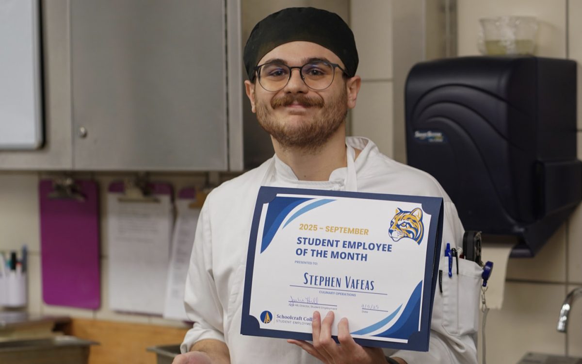 September Student Employee of The Month Stephen Vafeas, holds up his certificate of recognition.