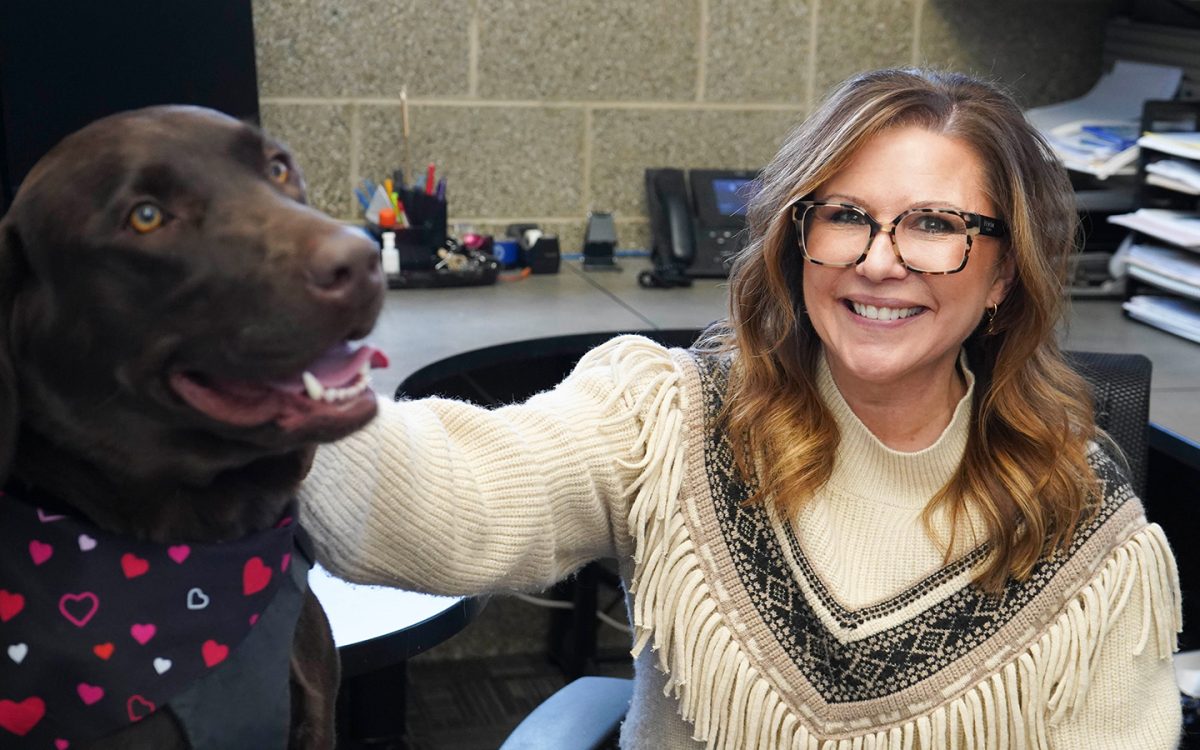 Mathematics Professor Andrea Mayes poses in her office with Schoolcraft College Comfort dog, Copper. 